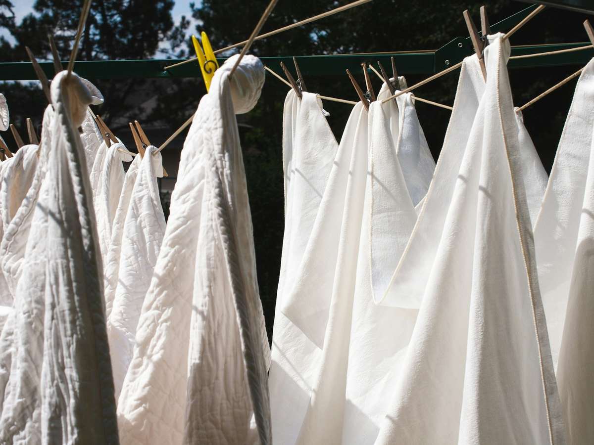Freshly washed white linen pegged out on a rotary clothesline in the sun